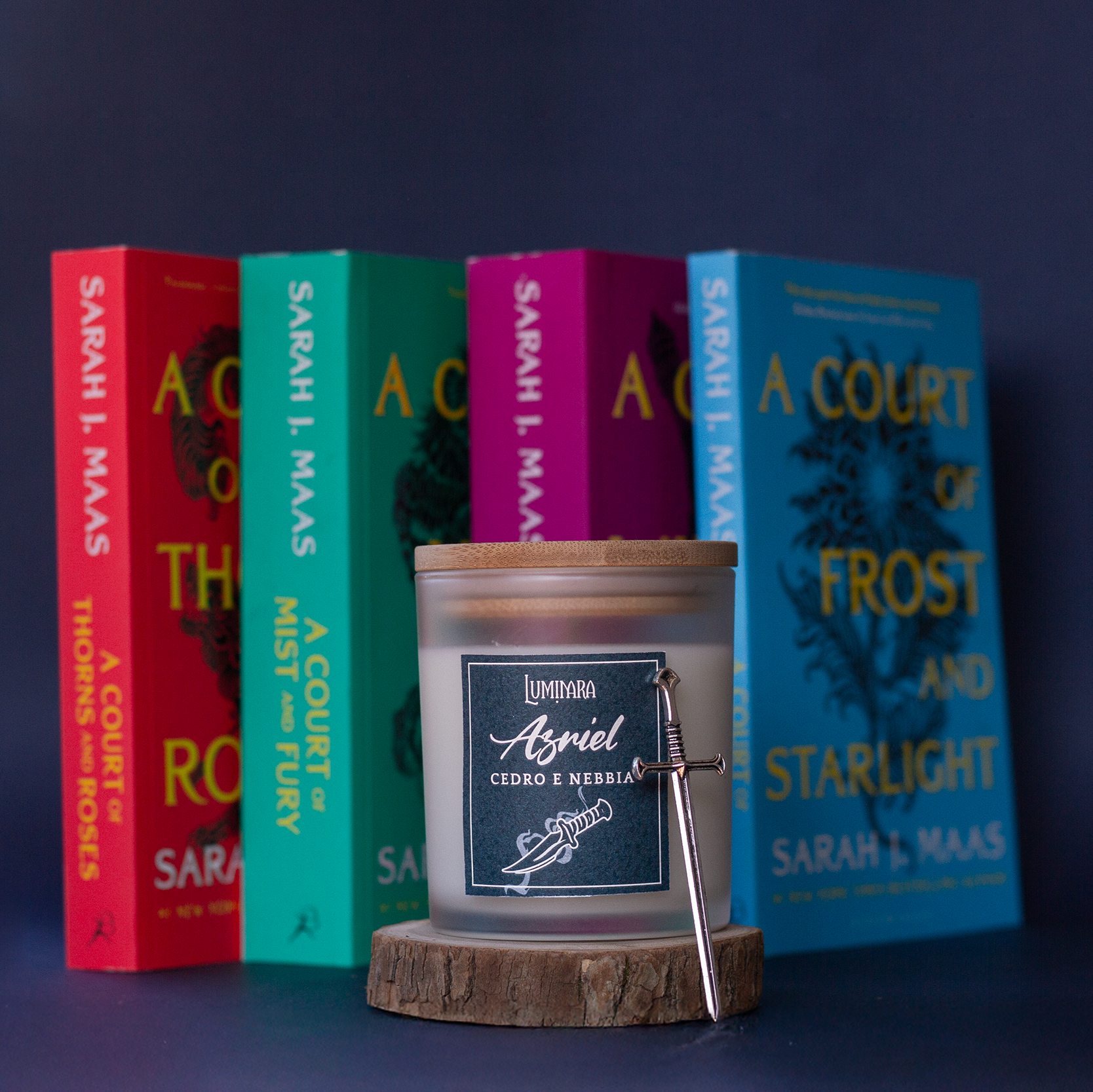 Candela in vetro con coperchio in bamboo, sull'etichetta il nome Azriel e Luminara Portali - Fragranza cedro e nebbia notturna, ispirata allo Spymaster e al Maasverse. sullo sfondo la Serie di libri ACOTAR