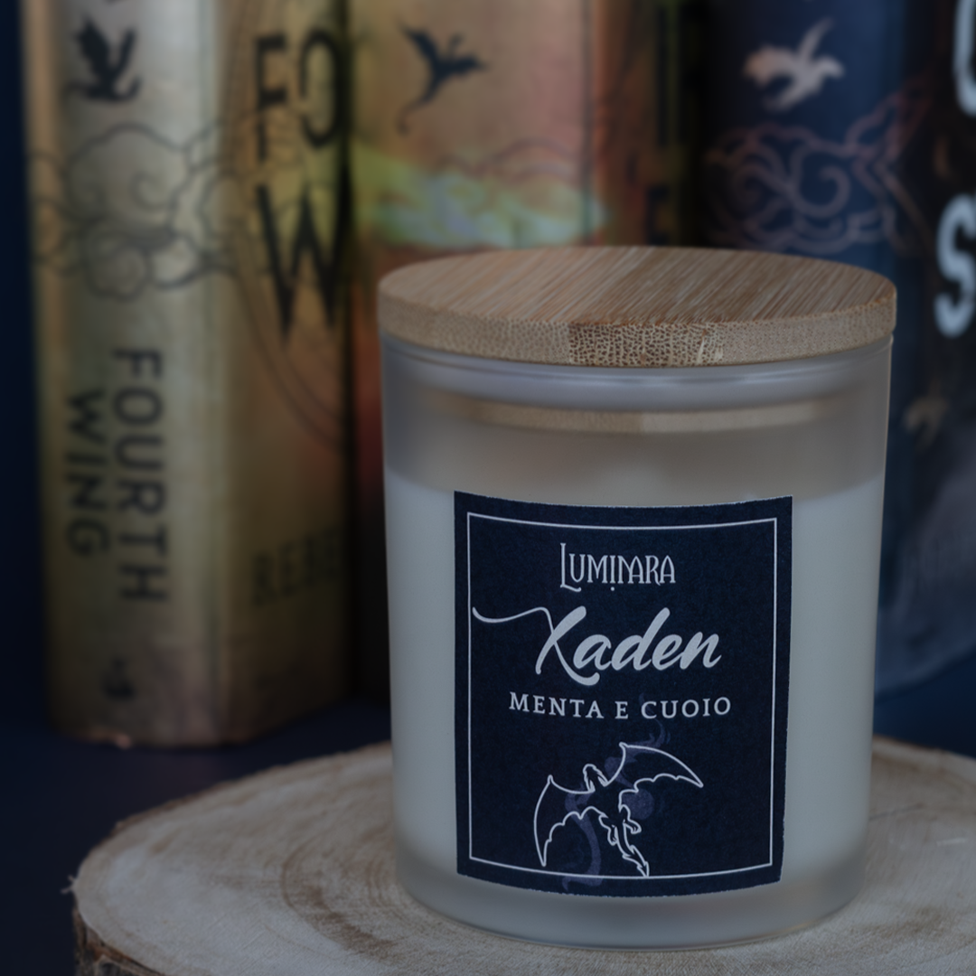 Candela elegante in vetro con tappo di bamboo, sull'etichetta è presente il nome Xaden e la profumazione menta e cuoio, ispirata a Fourth Wing e Iron Flame - Rebecca Yarros. sullo sfondo i libri fourth wing, iron flame e Onyx Storm di Yarros