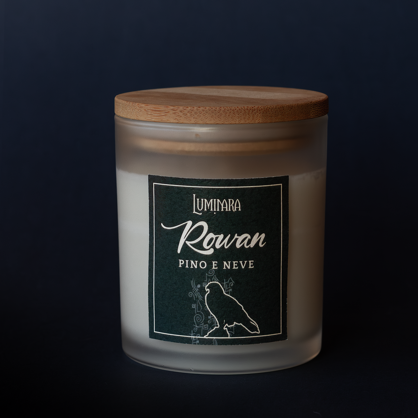 Candela elegante in vetro con tappo di bamboo, sull'etichetta è presente il nome Rowan e la profumazione pino e neve